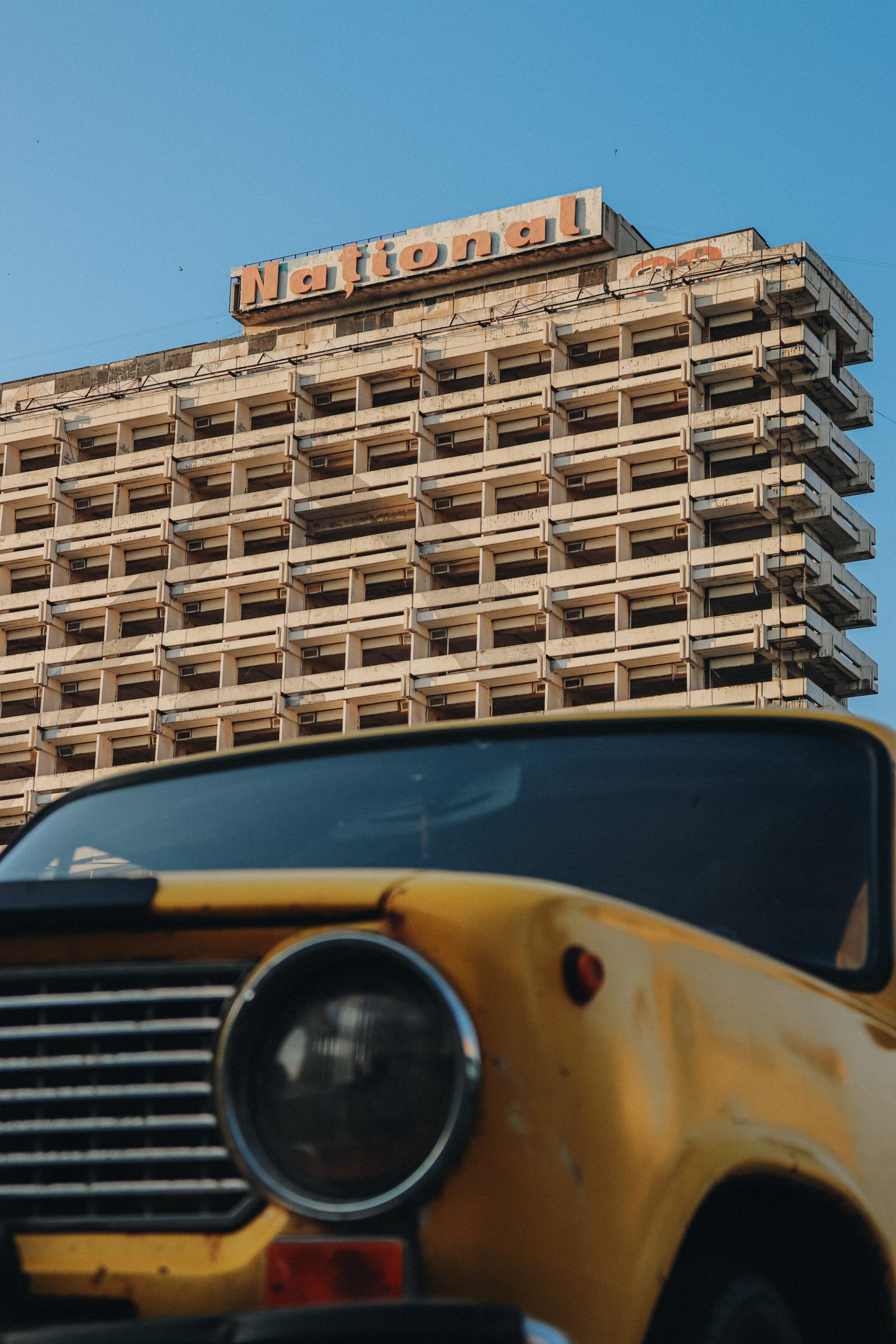 A close-up of a Zhiguli car, manufactured in Russia and the Soviet Union from 1970 to 2012, sold under the Lada brand. In the background, the Hotel National (formerly Intourist), built in 1978