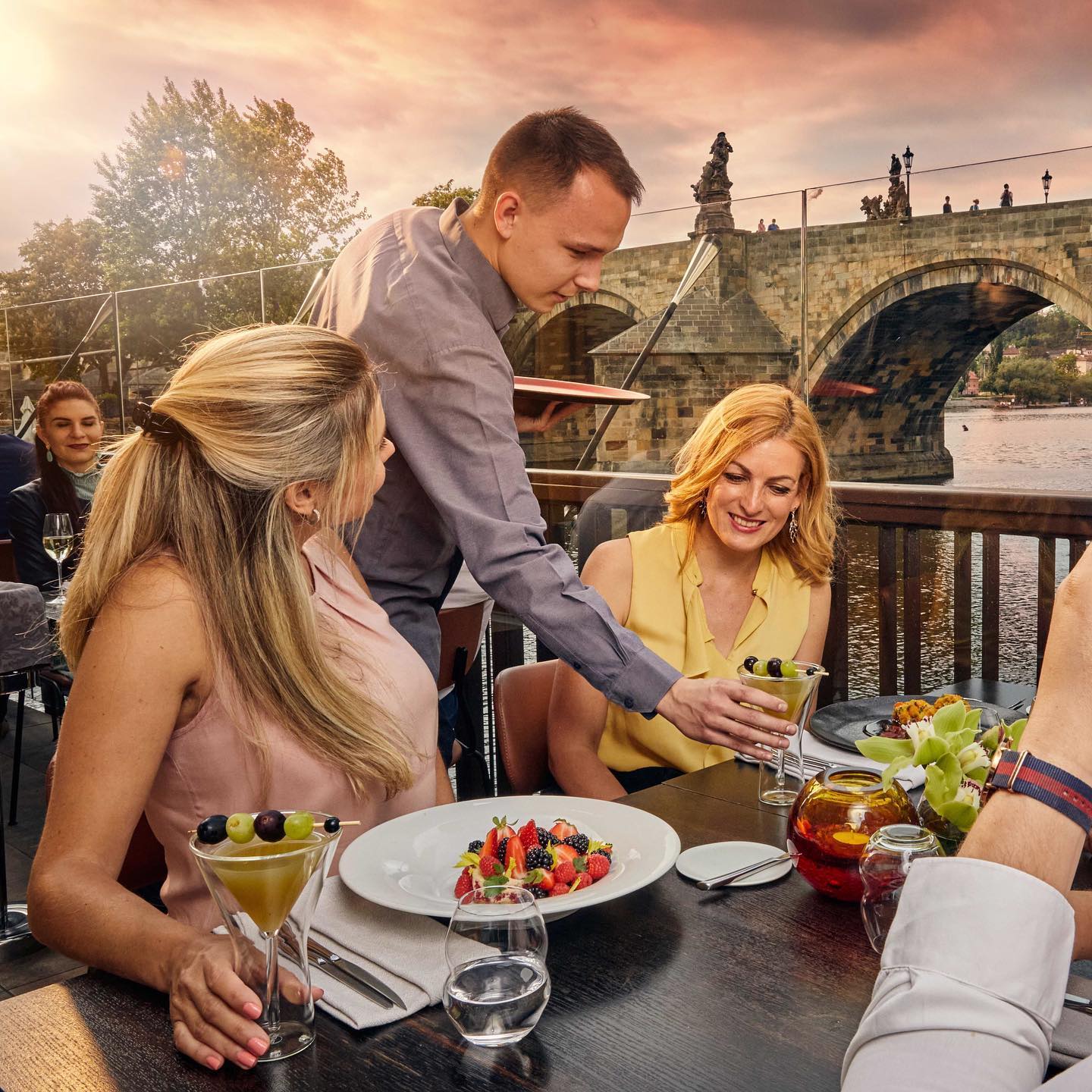 Enjoying cold drinks and good food on the patio of Mlýnec Restaurant during hot summer days while taking in romantic views of the Charles Bridge